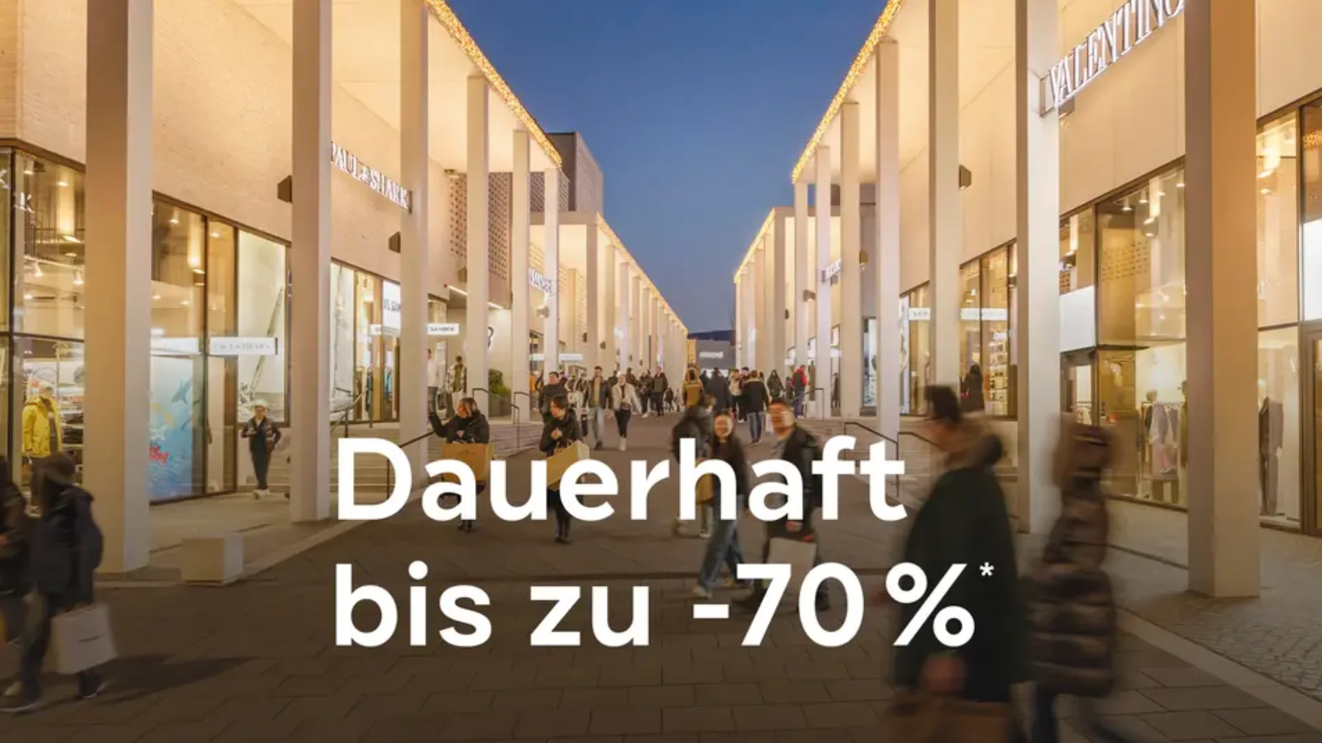 Blick auf einen Einkaufsbereich mit Menschen und Geschäften, Werbung für Rabatte bis zu -70%.